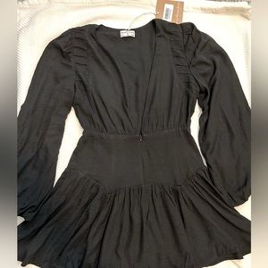 Seven Wonders Long sleeve black dress with plunging v neckline. Mini length